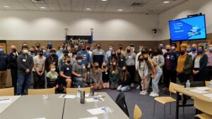 A large group of high school students and staff pose for a photo in a large room in Saint Anthony Village.