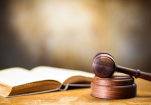 Stock image of an open law book beside a wooden gavel and sound block.