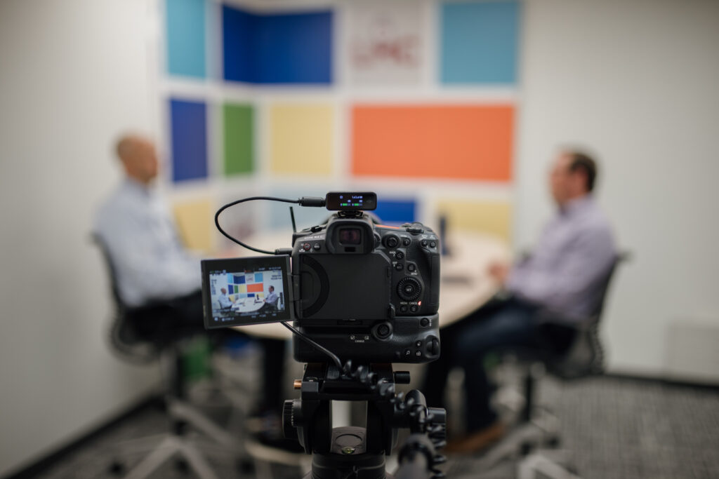 A camera is shown filming Luke Fischer and Brad Martens discussing Martens' transition to his leadership role as Shoreview's city administrator for Episode 2 of City Speak podcast's fifth season.