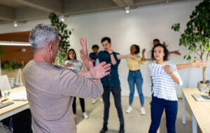 Man leading a group of workers stretching on an active break at the office.