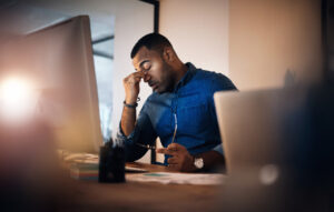 A young businessman looking stressed out while working in an office at night.