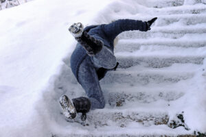 A woman slips and falls on a wintry staircase.