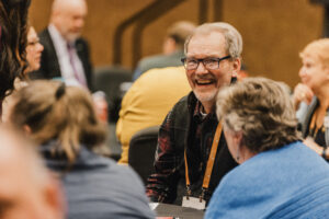 Person shown smiling with talking with other Elected Leaders Institute attendees