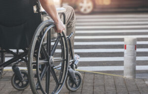 Person on wheelchair preparing to cross the road on pedestrian crossing