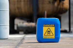 A blue gallon of hazard chemicals rests on the floor of a chemical factory, symbolizing the collective vigilance and teamwork required in the high-stakes environment. Collaboration and safety awareness in the chemical industry.