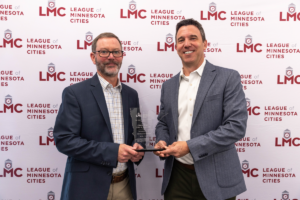 Clinton Rogers and Justin Miller stand in front of the League's step and repeat at the May 2025 LMC Board meeting