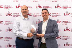 Dan Buchholtz and Justin Miller stand in front of the League's step and repeat at the May 2025 LMC Board meeting.
