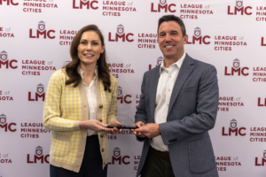 Jenny Max and Justin Miller stand in front of the League's step and repeat at the May 2025 LMC Board meeting.