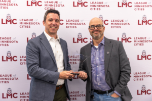 Justin Miller and Larry Odebrecht stand in front of the LMC step and repeat at the May 2025 LMC Board meeting