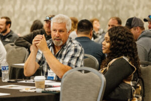 Loss Control attendees are shown conversing at a table during a session.