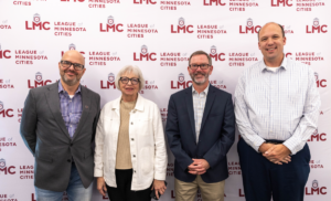 Outgoing LMC Board members Larry Odebrecht, Audrey Nelsen, Clinton Rogers, and Dan Buchholtz stand in front of the League's step and repeat at the May 2025 Board meeting.