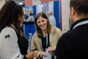 Three people chatting at the LMC Annual Conference exhibit hall. Person facing the camera is laughing and smiling.