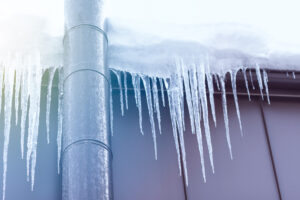 Frosted chimney pipe and icicles hanging from eaves of roof
