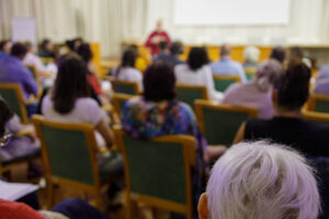 People listening to speaker in a conference room where a public meeting is held.